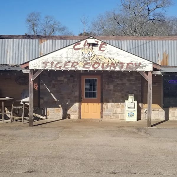 Exterior of Tiger Country Cafe, a rustic building with a tiger logo and "Cafe Tiger Country" on its facade.