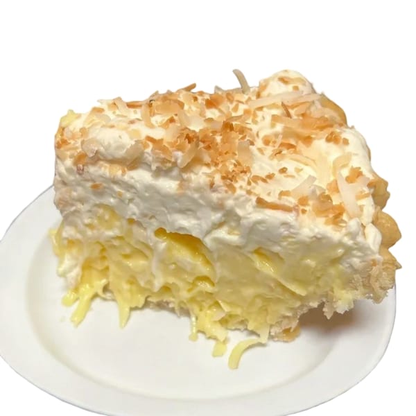 A slice of coconut cream pie with whipped topping and toasted coconut flakes on a white plate.